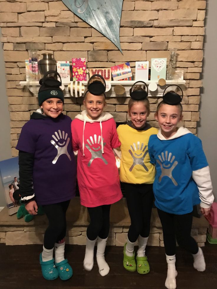 three girls standing next to each other in front of a brick wall wearing matching outfits