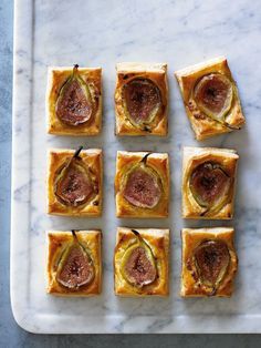 small sandwiches with figs and cheese on a white tray next to a blue marble counter top