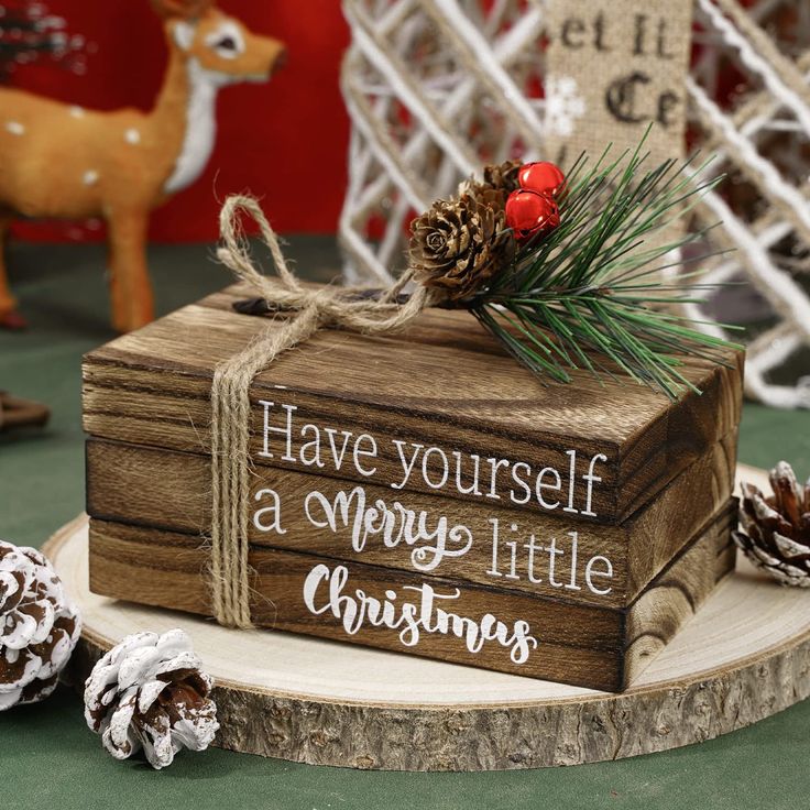 a small wooden box with pine cones on it and a sign that says have yourself a merry little christmas