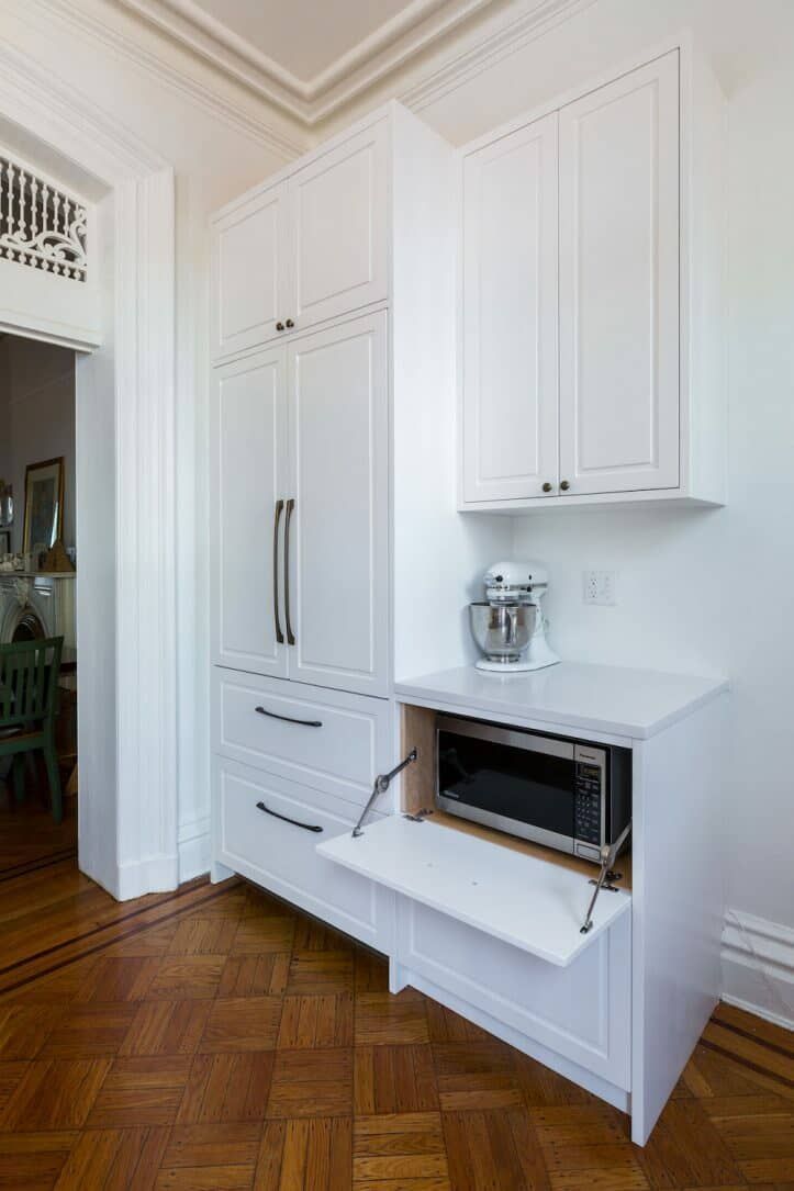 a kitchen with white cupboards and an oven on the counter in front of it