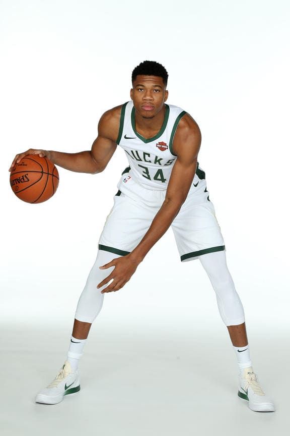 a man holding a basketball while standing in front of a white background with his hands on the ball