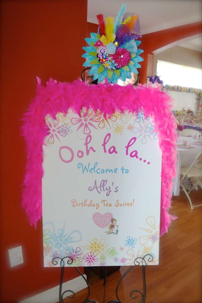 a welcome sign with pink feathers and flowers on it in front of an orange wall