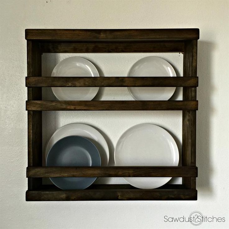 a wooden shelf holding plates and bowls on it's side, against a white wall