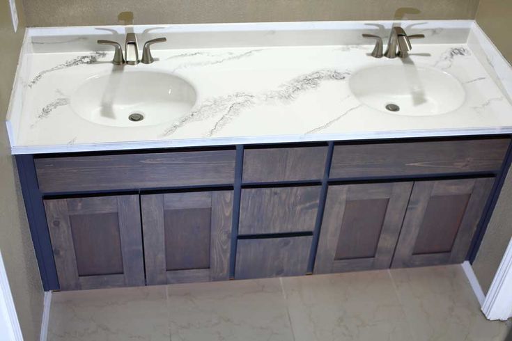 two white sinks sitting next to each other on top of a bathroom vanity with marble counter tops