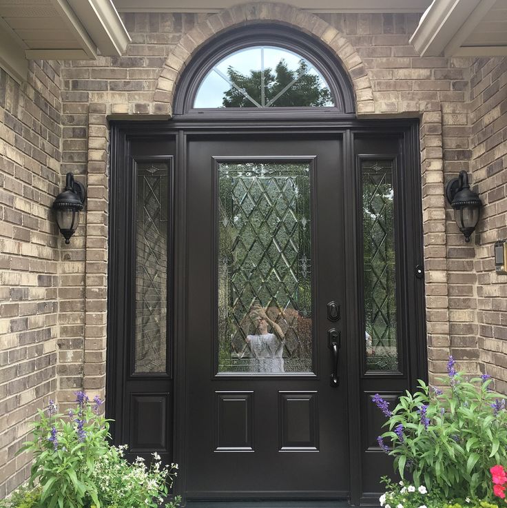 two dogs standing at the front door of a brick house with glass panels on it