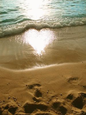 two footprints in the sand with a heart shape drawn on it's beach shore