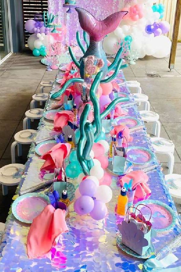 a long table covered in lots of balloons and other items for a mermaid themed party