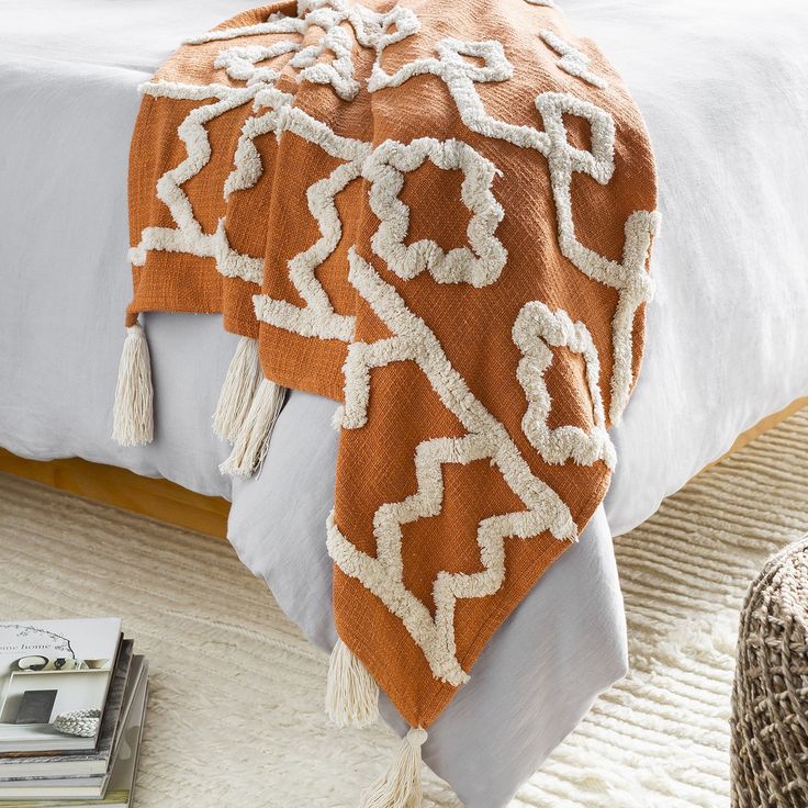 an orange and white blanket sitting on top of a bed