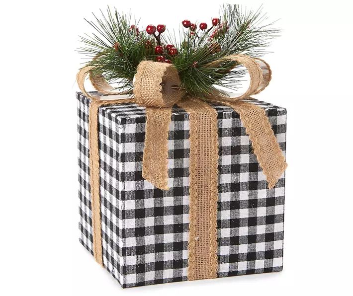 a christmas present wrapped in black and white checkered paper with pine branches on top