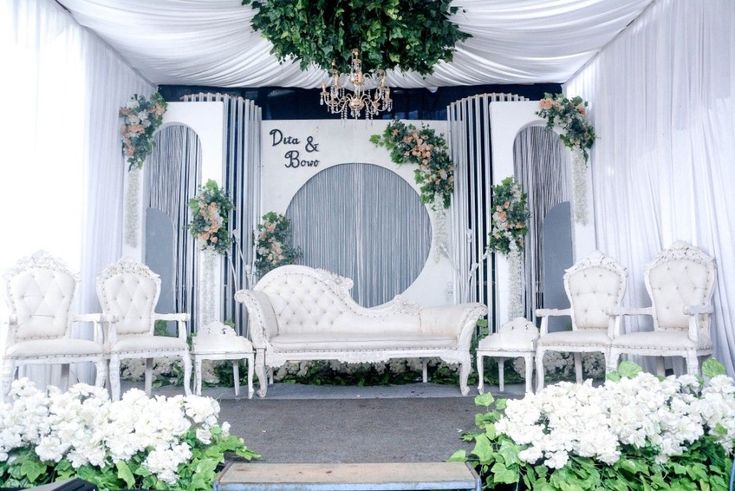 a stage set up with white furniture and flowers