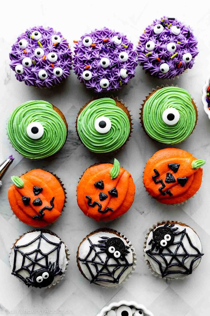 halloween cupcakes decorated with green icing and spooky eyes are arranged on a marble surface