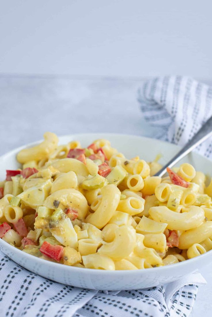 a white bowl filled with macaroni salad on top of a blue and white towel