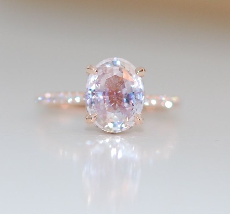 an oval shaped pink diamond ring on a white surface