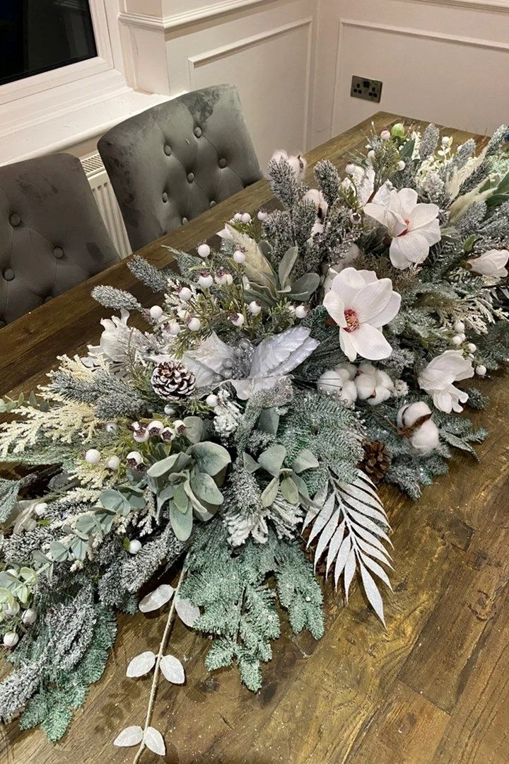 a wooden table topped with flowers and greenery