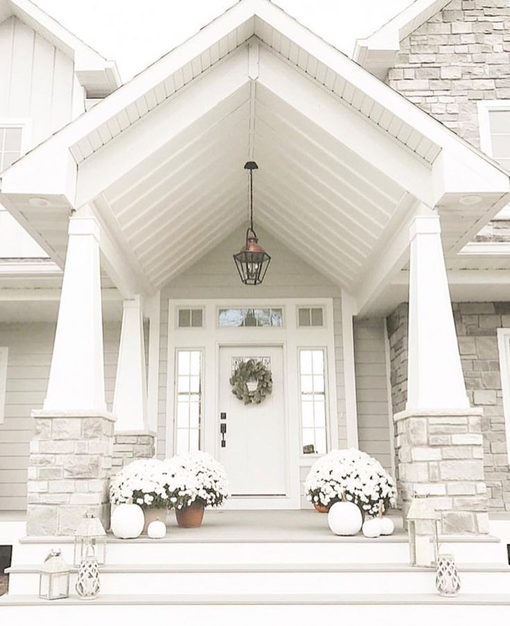 a white front door with two planters on the steps and a lantern hanging above it