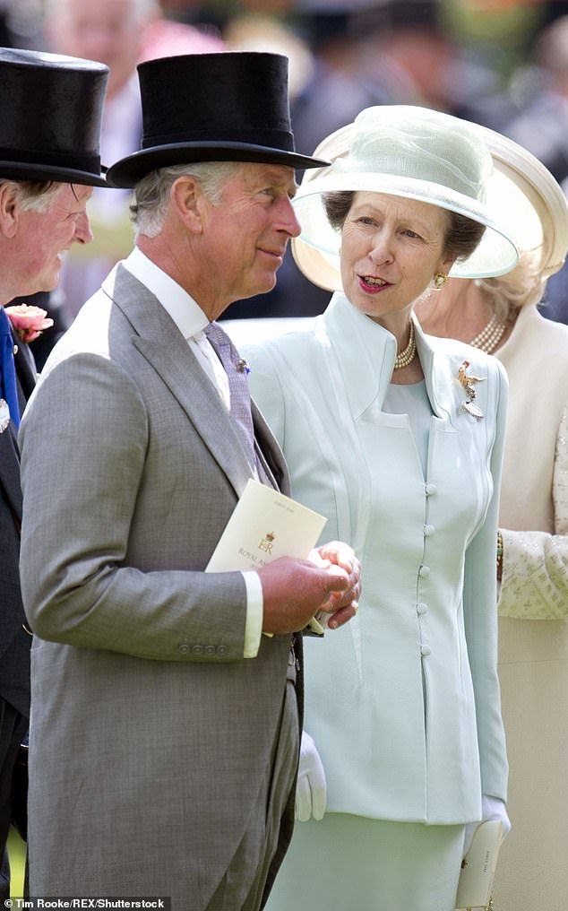 two men and a woman wearing hats talking to each other at an outdoor event with people in the background