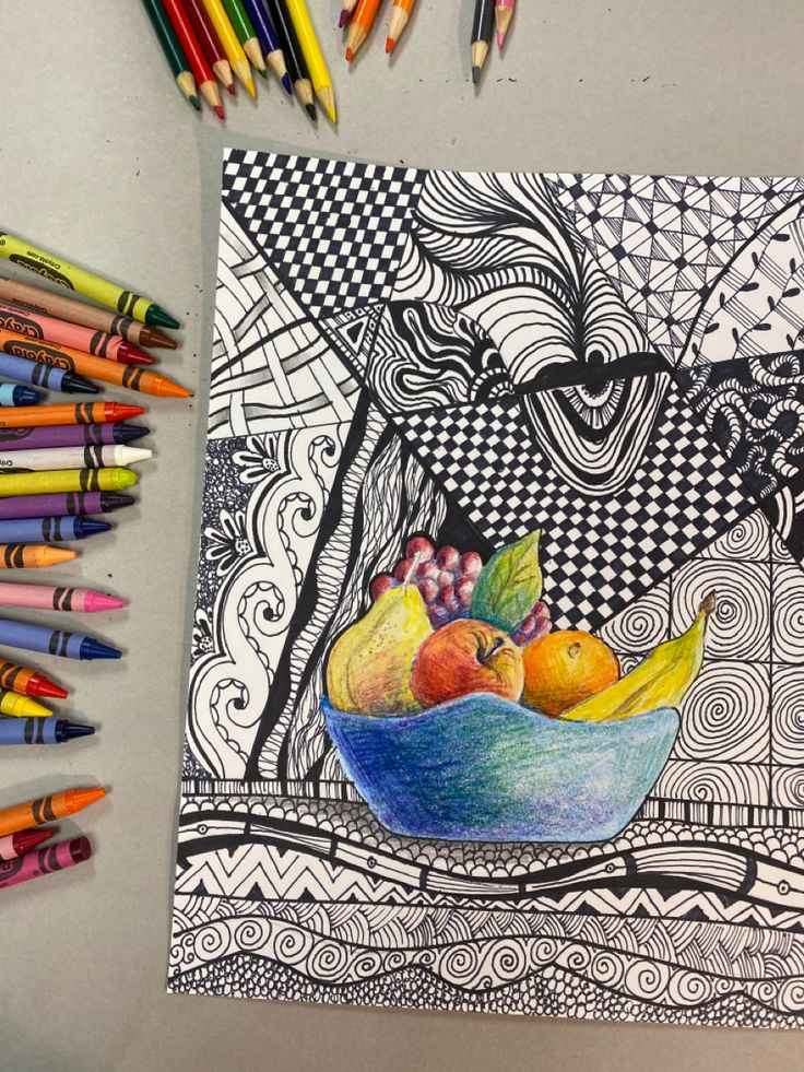 colored pencils are next to a drawing of fruit in a bowl