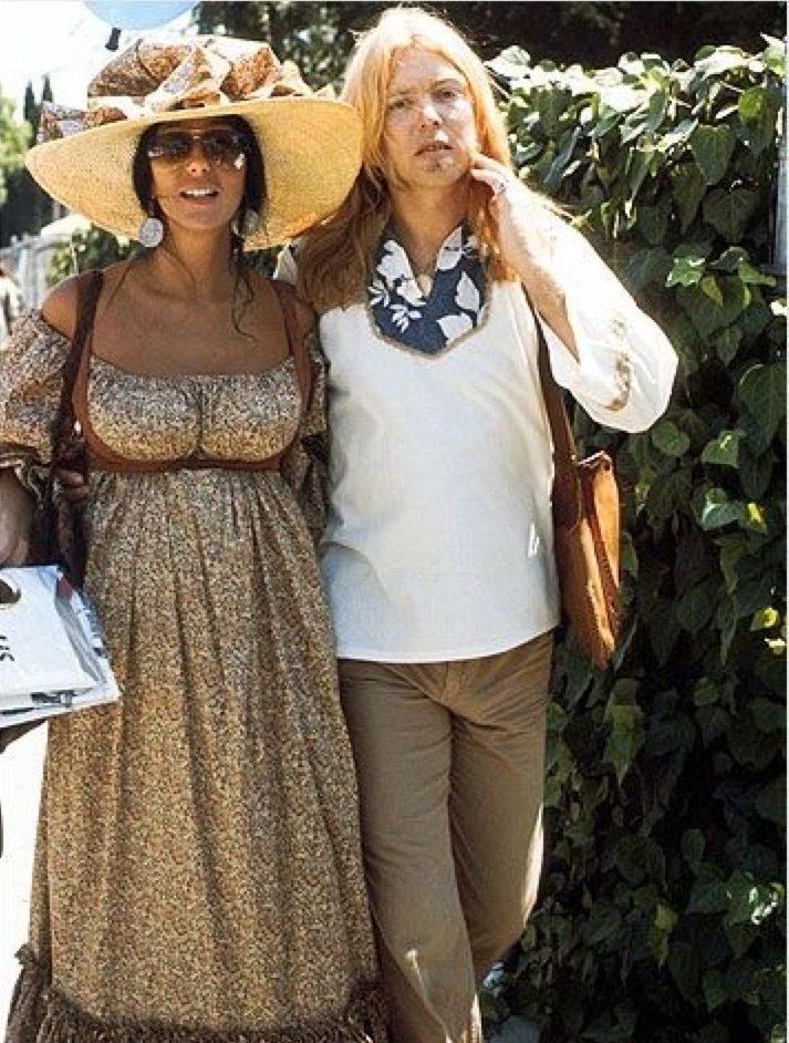 two women are standing next to each other and one is wearing a large sun hat