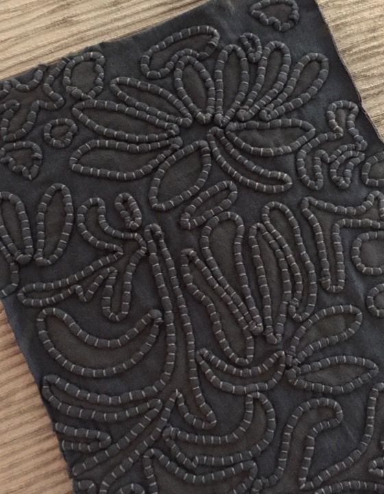 a piece of black cloth with an intricate design on it, sitting on a wooden surface