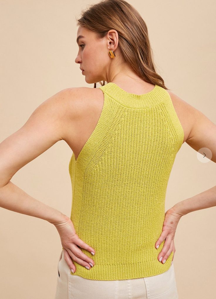 a woman with her back to the camera, wearing a yellow top and white pants