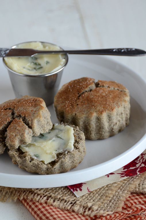 two biscuits on a white plate with a bowl of cream cheese and a spoon in the background