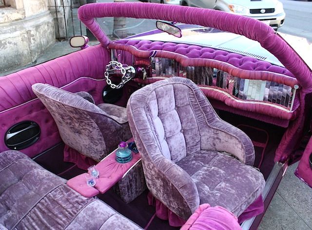 the interior of an old fashioned car with purple velvet upholstered seats and pink carpet