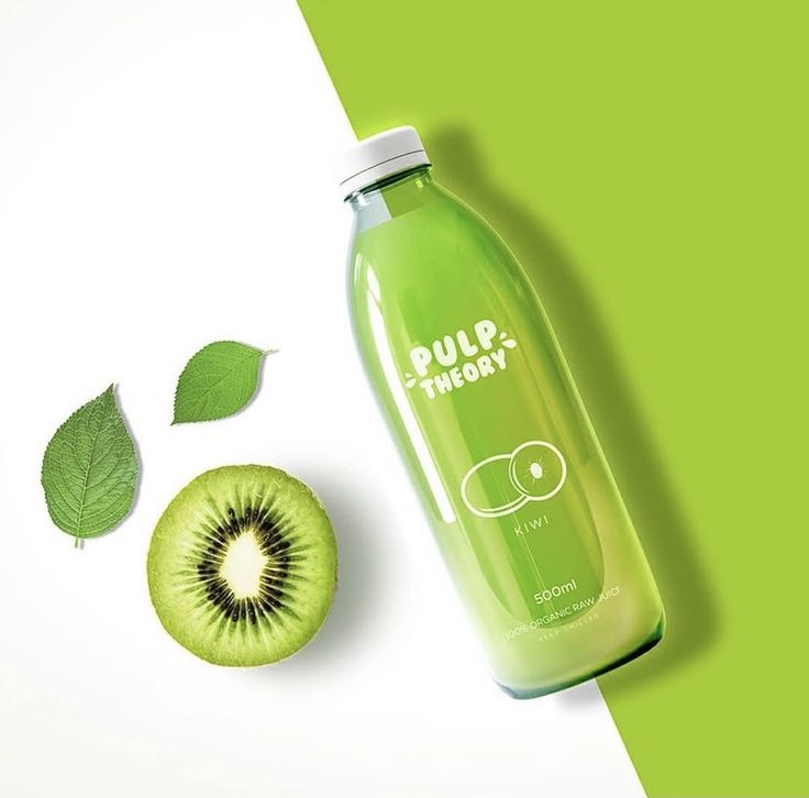 a bottle of green liquid next to a kiwi