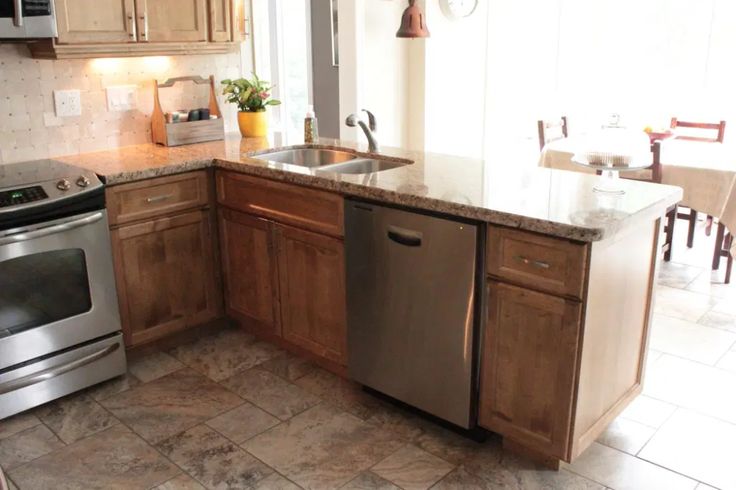 a kitchen with stainless steel appliances and wooden cabinets, marble counter tops and tile flooring