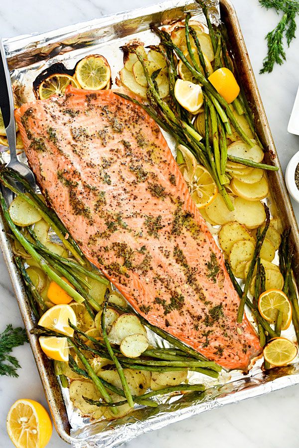 salmon, potatoes and asparagus in a baking pan with lemons on the side