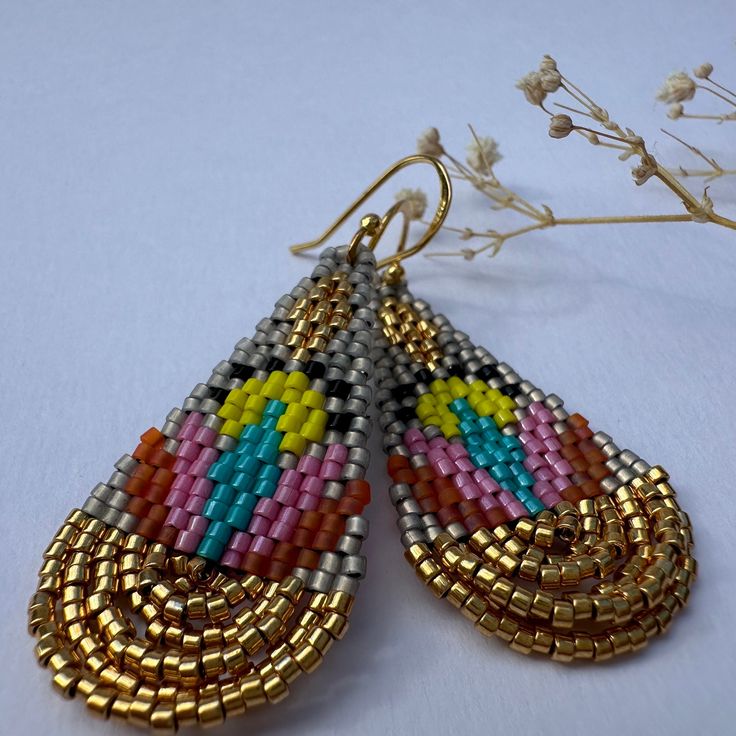 Introducing the "Lotus Gold" earrings, a dazzling fusion of vibrant colors and elegant design. These handcrafted earrings are inspired by the beauty of lotus flowers and crafted with meticulous attention to detail. Materials: High-quality seed beads in various colors, silver and gold tone sterling silver 925 ear hooks. Weight: 2g each Length:  5.5 cm Width: 2 cm Care Instructions: To maintain the beauty of your earrings, avoid direct contact with water, perfume, and harsh chemicals. Store them i Water Perfume, Lotus Flowers, Delica Beads, Handcrafted Earrings, Ear Hook, Silver And Gold, Sterling Earrings, Beaded Earrings, Silver 925