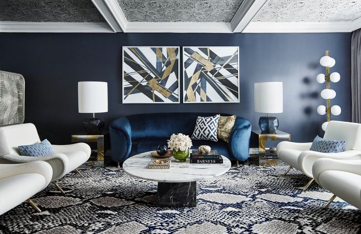 a living room filled with white furniture and blue wall art above the couches is a coffee table surrounded by two chairs