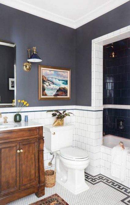 a white toilet sitting next to a bath tub in a bathroom under a framed painting