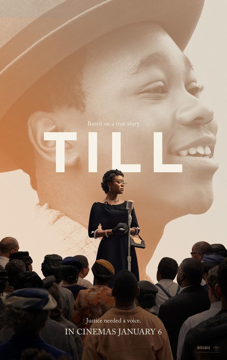 a woman standing in front of a crowd with a movie poster on the wall behind her