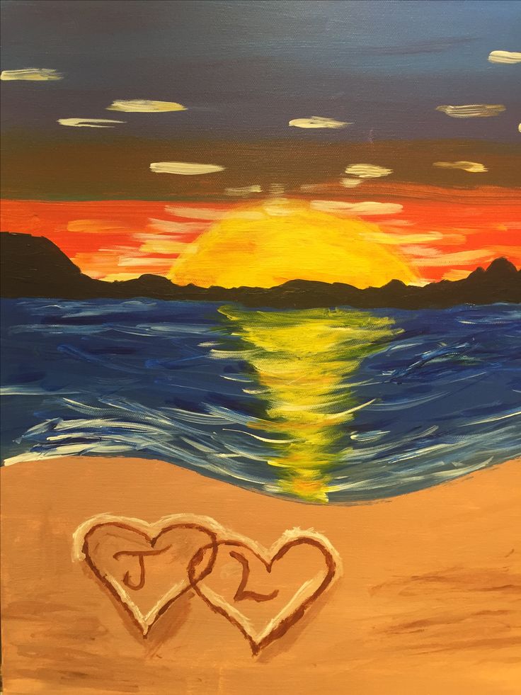 two hearts drawn in the sand on a beach at sunset with water and mountains behind them