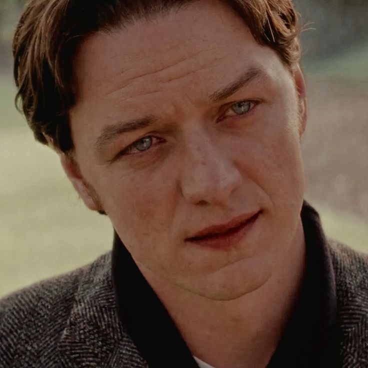 a close up of a person wearing a suit and tie with an open collared shirt