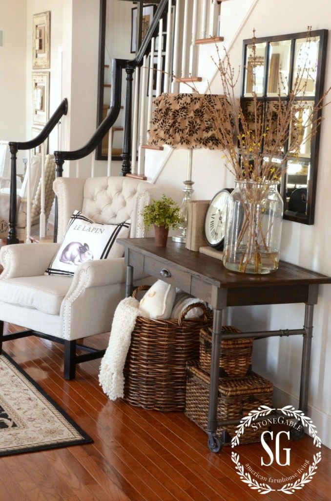 a living room filled with furniture next to a stair case and mirror wall hangings