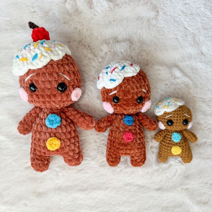 three crocheted teddy bears sitting next to each other on a white blanket,