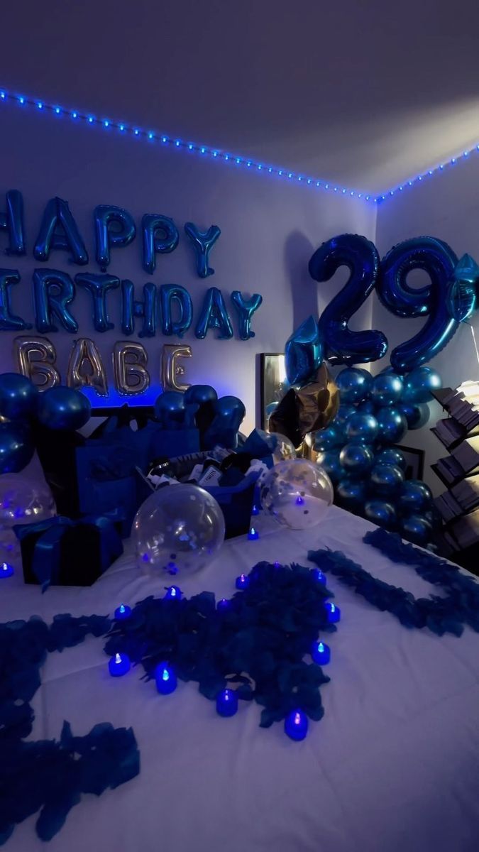 a bed with blue balloons and streamers on it in a room decorated for a birthday