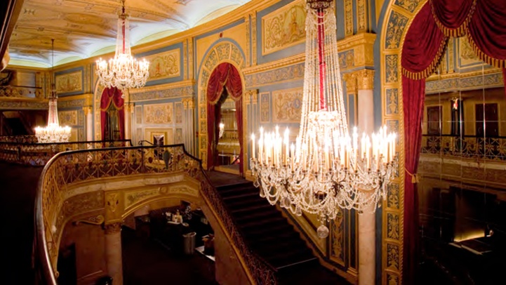 chandelier hanging from the ceiling in an ornately decorated room with red curtains