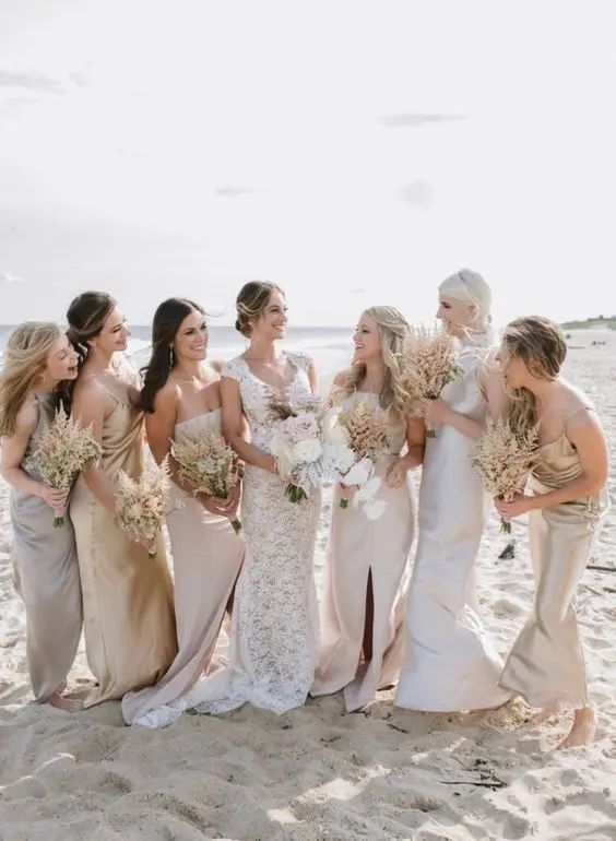 a group of women standing next to each other on top of a sand covered beach