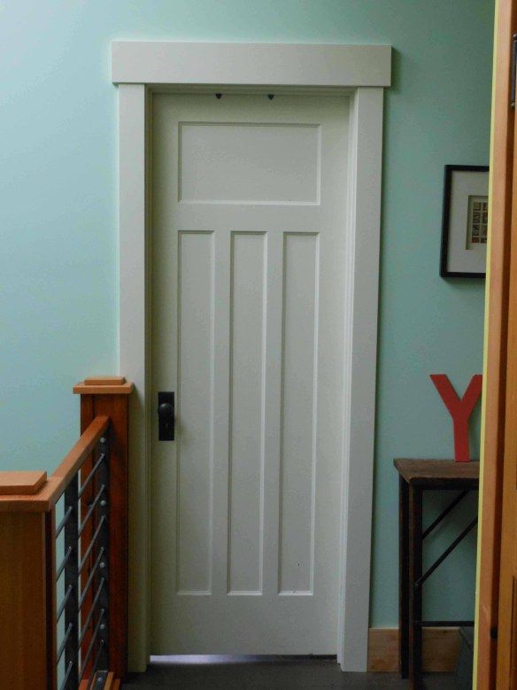 a white door is in the corner of a room with blue walls and wooden stairs