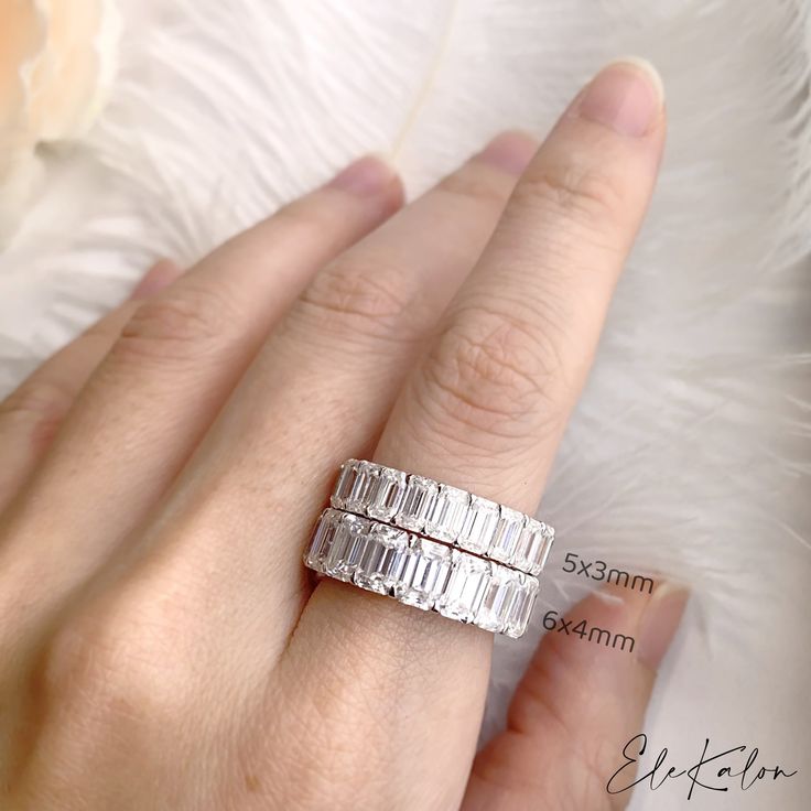 a woman's hand with two rings on her finger and the ring has three baguettes in it