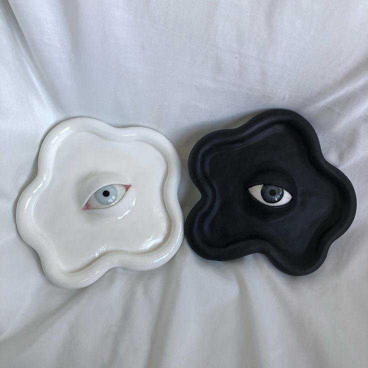 two black and white plates with eyeballs on them are laying on a bed sheet