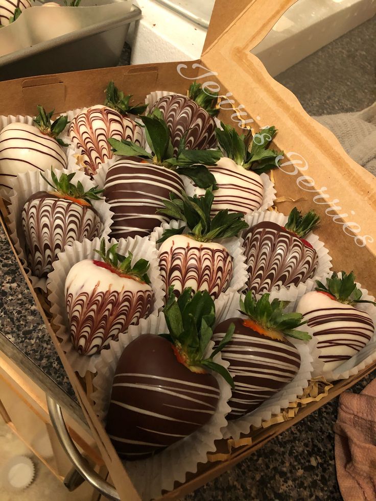 chocolate covered strawberries sit in a box on the counter top, ready to be eaten