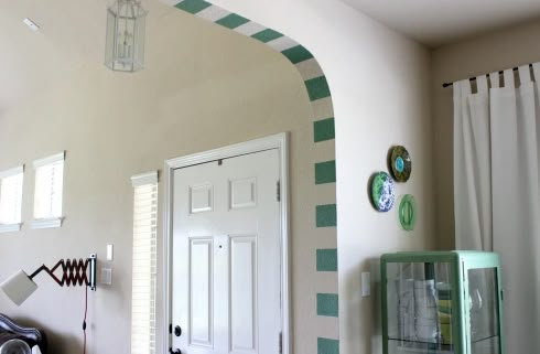 a living room with a white door and green trim on the wall next to a window