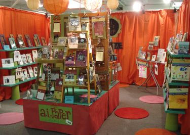 an orange tent with lots of books on display in front of red curtains and round rugs