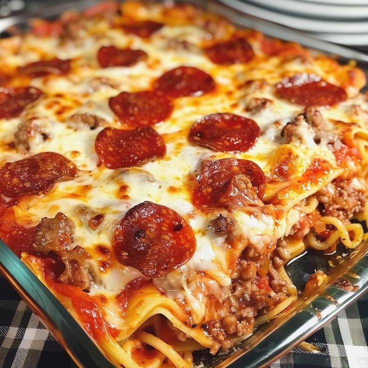 a pizza casserole with pepperoni and cheese on it is sitting on a table