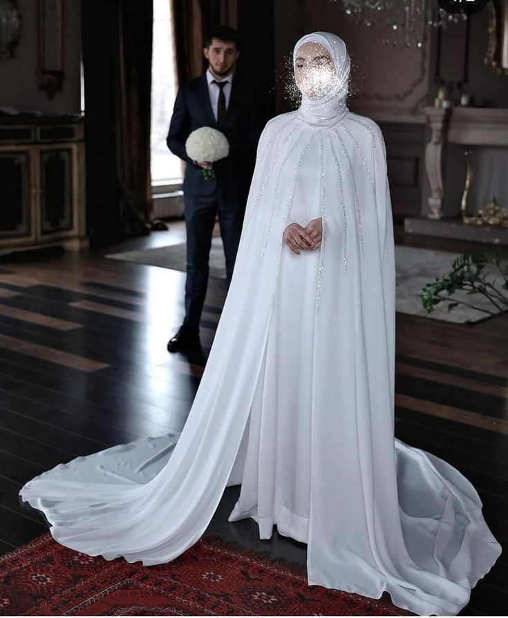 a man standing next to a woman in a white wedding dress and veil on her head