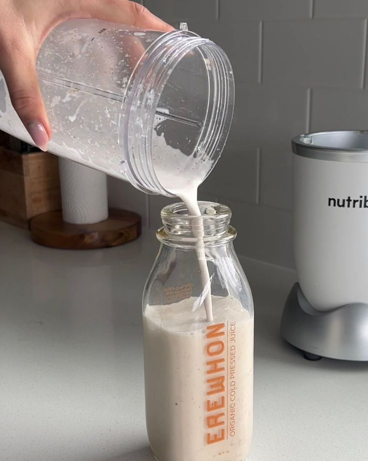 a person pouring milk into a glass jar