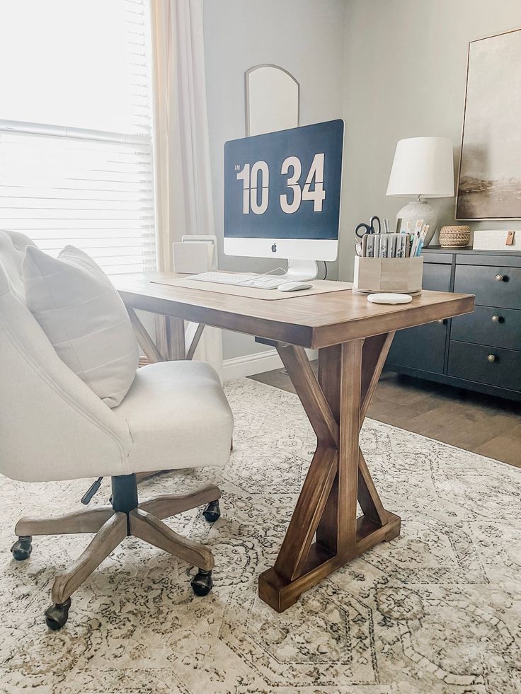 a desk with a clock on it and a chair next to it in front of a window